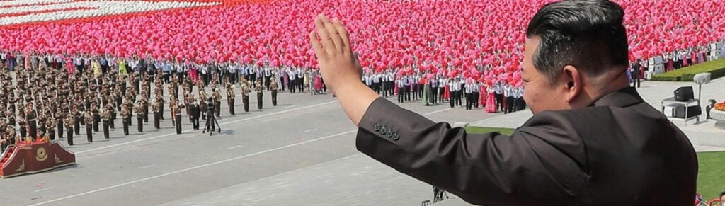 Kim Jong-Un met volk op de achtergrond in Noord-Korea