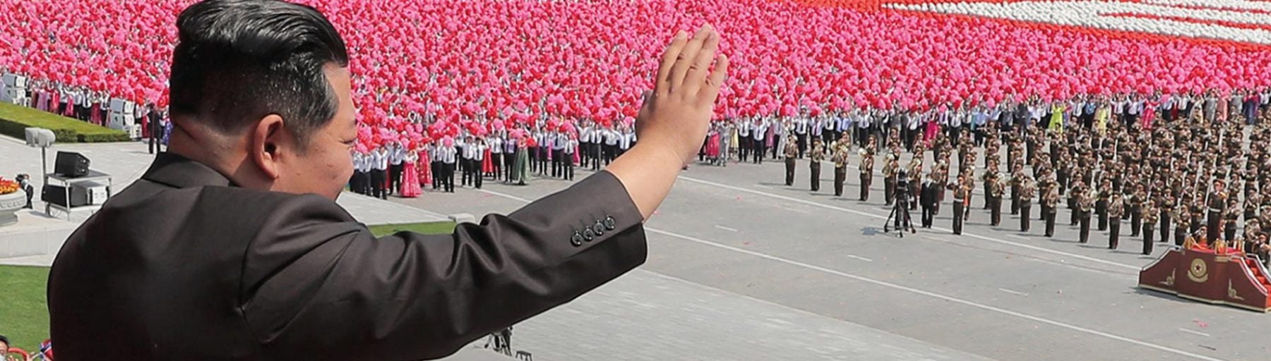 Kim Jong-Un met volk op de achtergrond in Noord-Korea